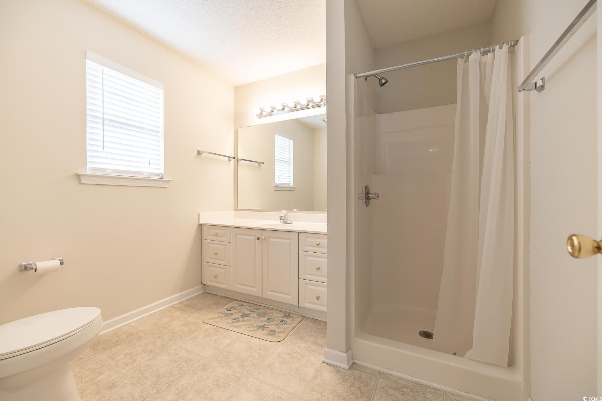 5077 Capulet Circle Myrtle Beach, SC 29588 - Photo 12 of 27 Full bathroom with a stall shower, vanity, light tile patterned floors, and a textured ceiling