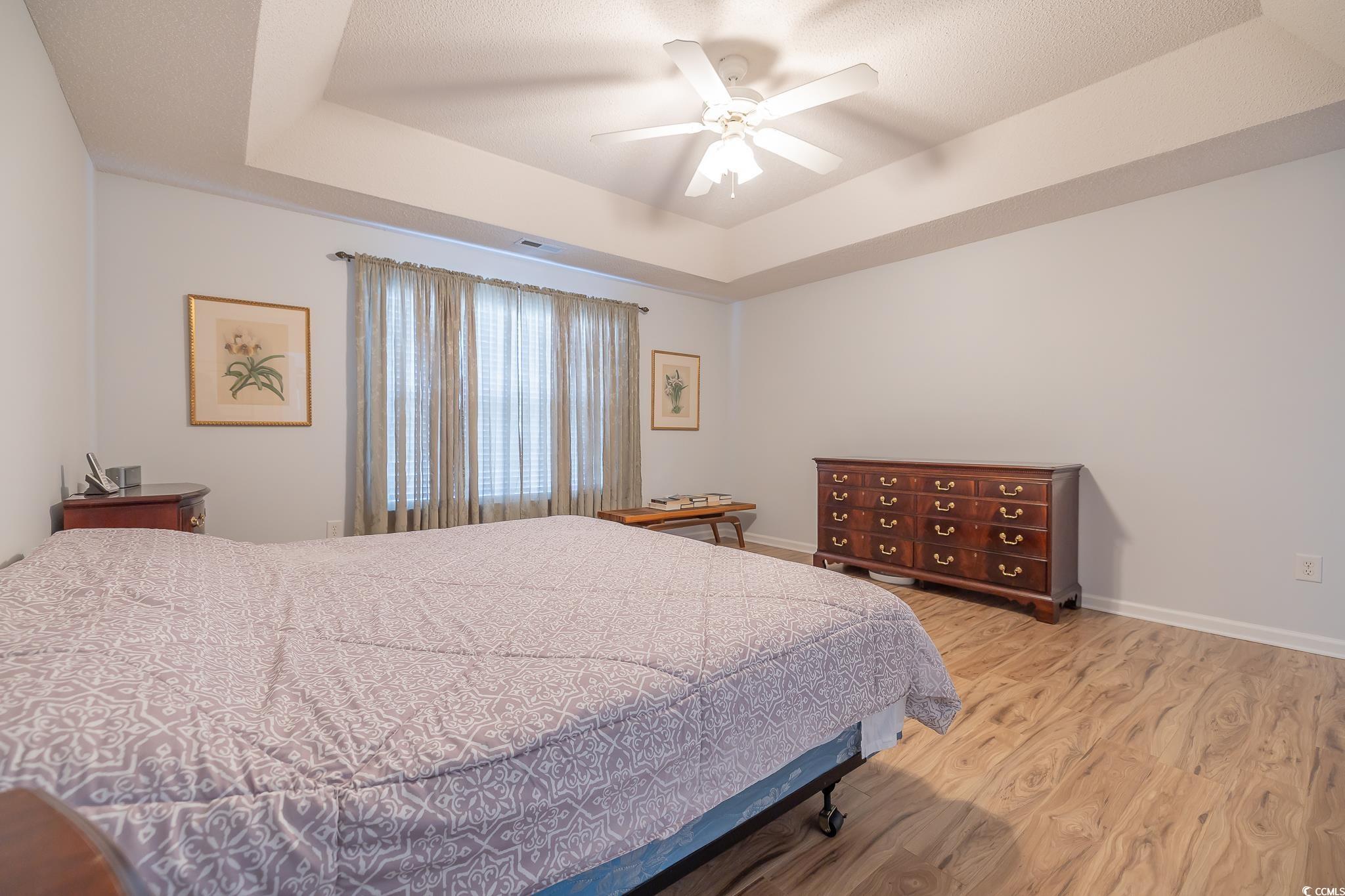 5077 Capulet Circle Myrtle Beach, SC 29588 - Photo 15 of 27 Bedroom with a tray ceiling, light wood-style flooring, and a ceiling fan