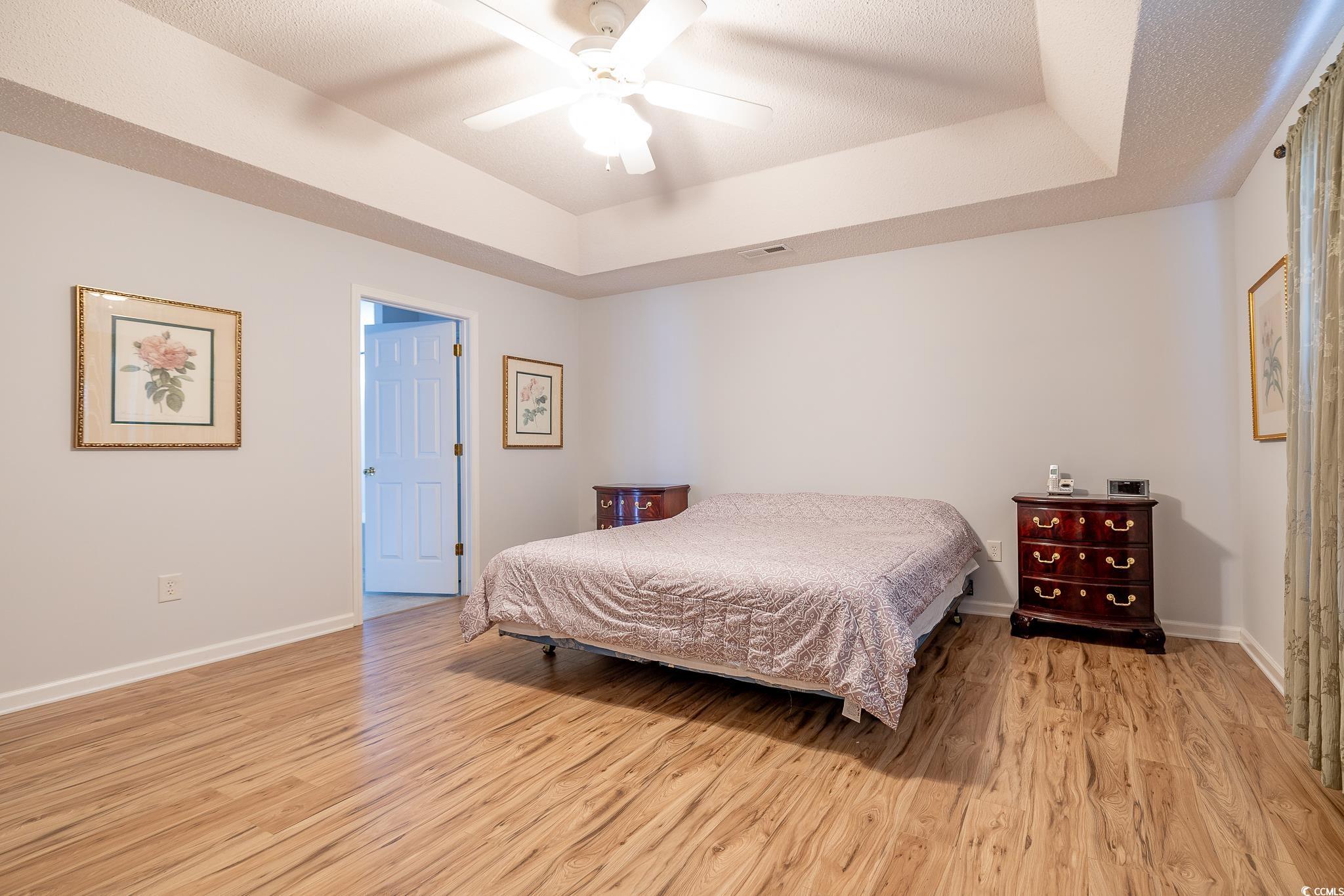 5077 Capulet Circle Myrtle Beach, SC 29588 - Photo 19 of 27 Bedroom featuring a raised ceiling, light wood-style floors, and ceiling fan