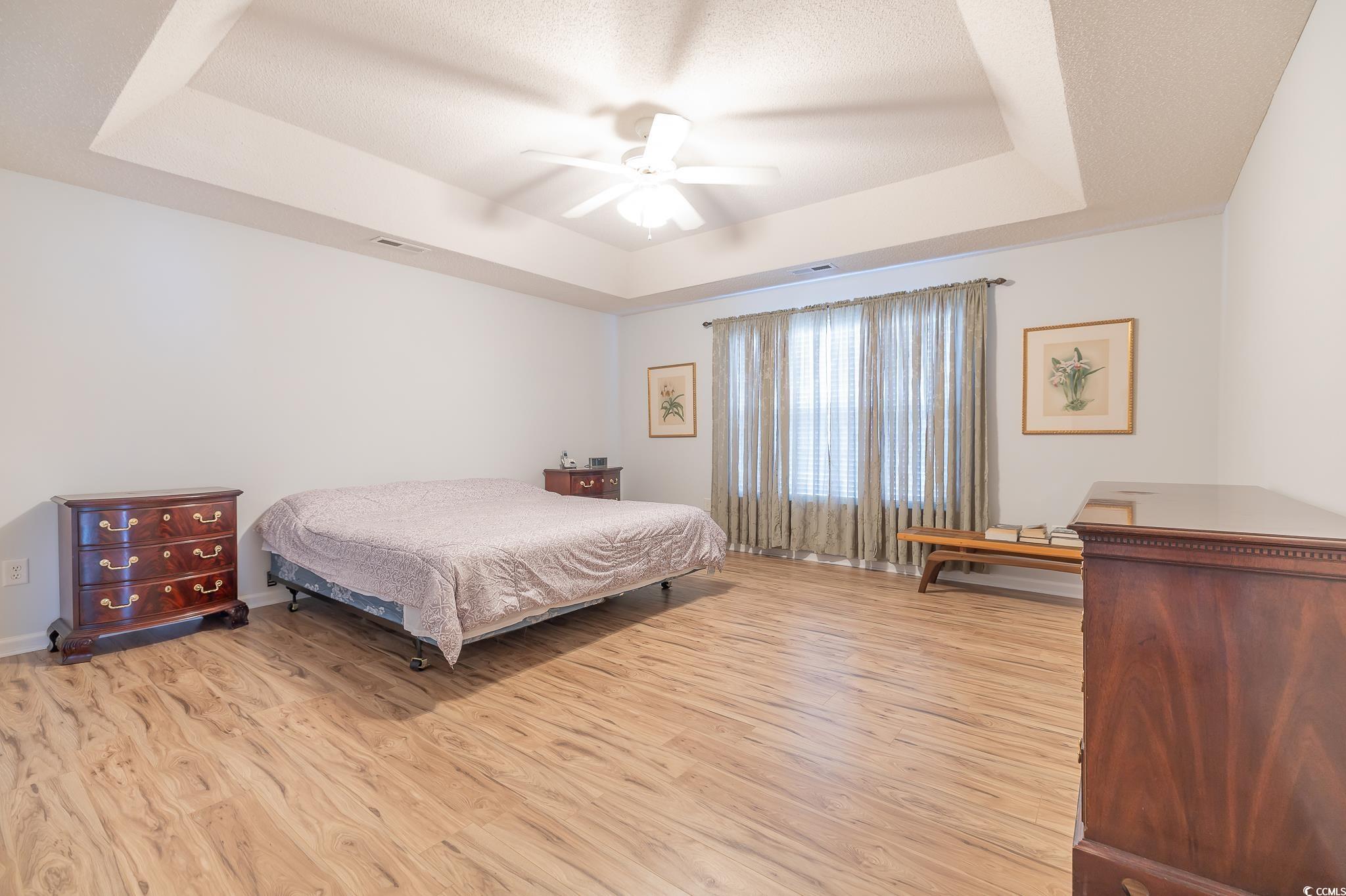 5077 Capulet Circle Myrtle Beach, SC 29588 - Photo 20 of 27 Bedroom with a raised ceiling, light wood-style floors, and ceiling fan