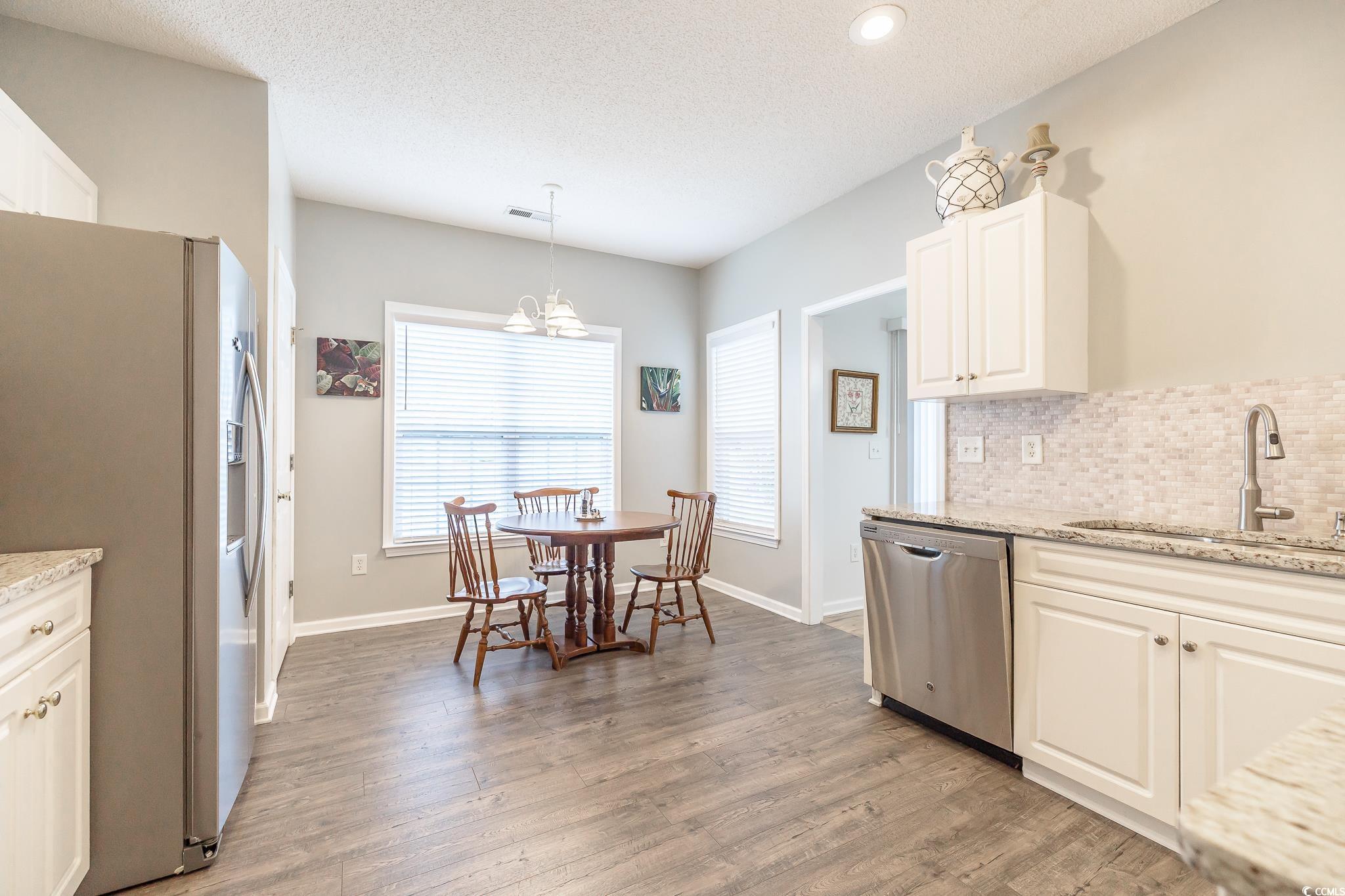 5077 Capulet Circle Myrtle Beach, SC 29588 - Photo 24 of 27 Kitchen featuring light stone countertops, stainless steel appliances, tasteful backsplash, white cabinetry, and a textured ceiling