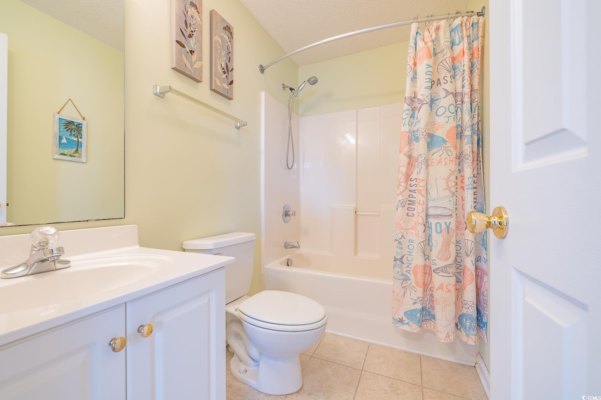 5077 Capulet Circle Myrtle Beach, SC 29588 - Photo 25 of 27 Bathroom featuring shower / bathtub combination with curtain, vanity, light tile patterned flooring, and a textured ceiling