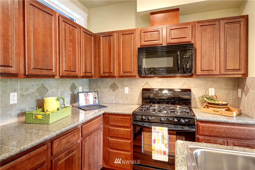 907 225th Place Southeast Bothell, WA 98021 - Photo 8 of 20 a kitchen with granite countertop a stove top oven microwave and cabinets