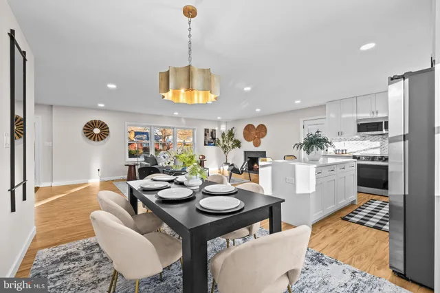 a kitchen with stainless steel appliances granite countertop a refrigerator a stove top oven a sink dishwasher and white cabinets with wooden floor