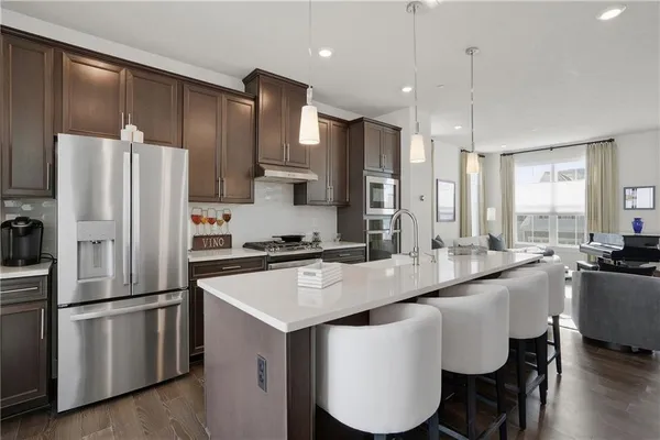 a kitchen with stainless steel appliances a refrigerator a sink a stove a dining table and chairs