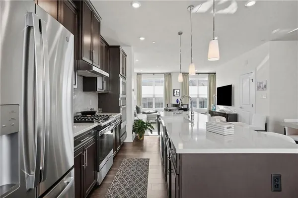 a kitchen with stainless steel appliances a stove a sink a refrigerator and a center island