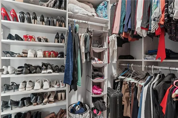 a view of walk in closet with clothes and shoes