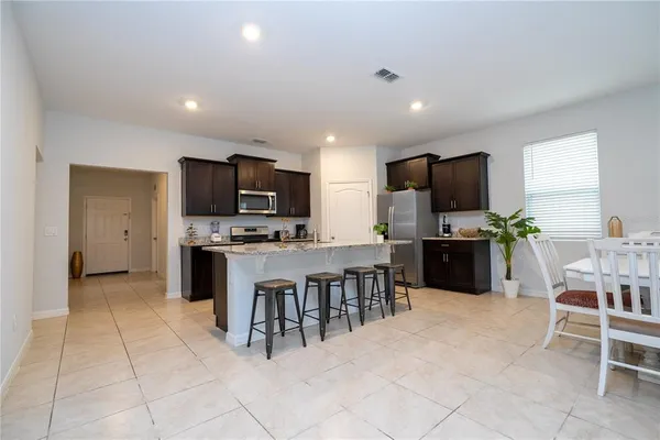 a kitchen with stainless steel appliances granite countertop a refrigerator a stove a sink a microwave and chairs