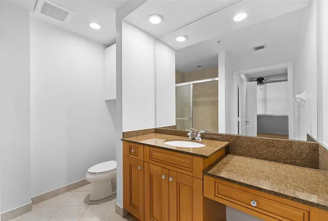 a bathroom with a granite countertop sink a toilet and a mirror