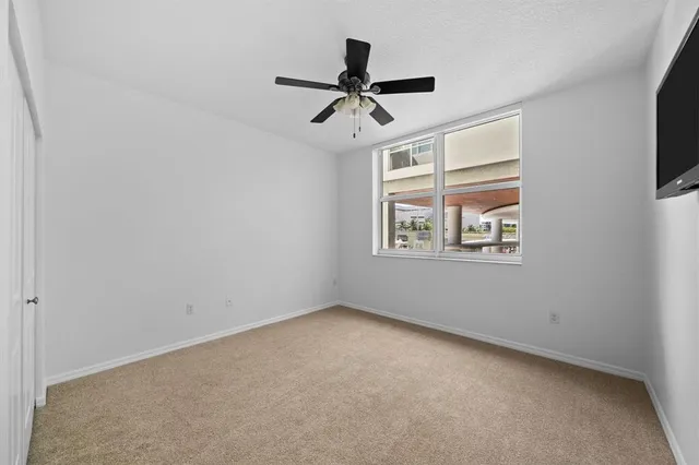 an empty room with windows and ceiling fan
