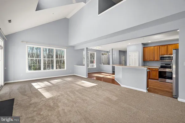 a kitchen with stainless steel appliances a refrigerator a sink dishwasher a stove top oven a dining table and chairs with wooden floor