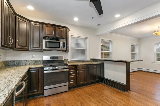 a kitchen with stainless steel appliances granite countertop wooden cabinets a stove top oven a sink and dishwasher