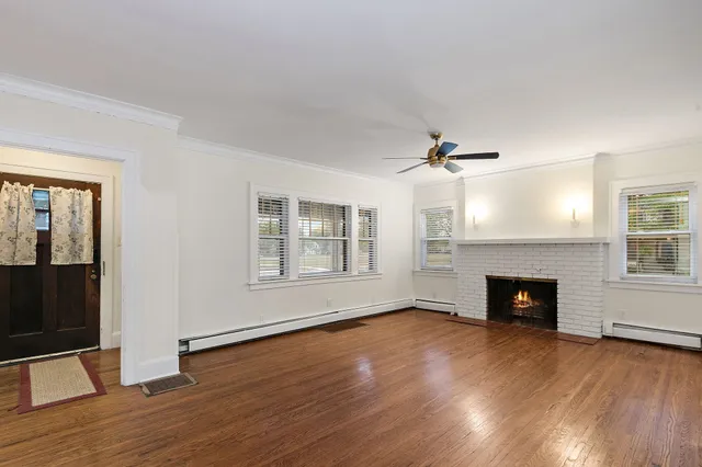 an empty room with windows fireplace and wooden floor