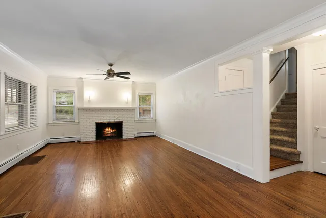 an empty room with wooden floor fireplace and windows