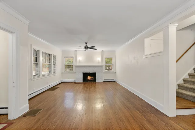 a view of an empty room with wooden floor fireplace and a window