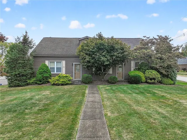 a front view of a house with a yard and potted plants
