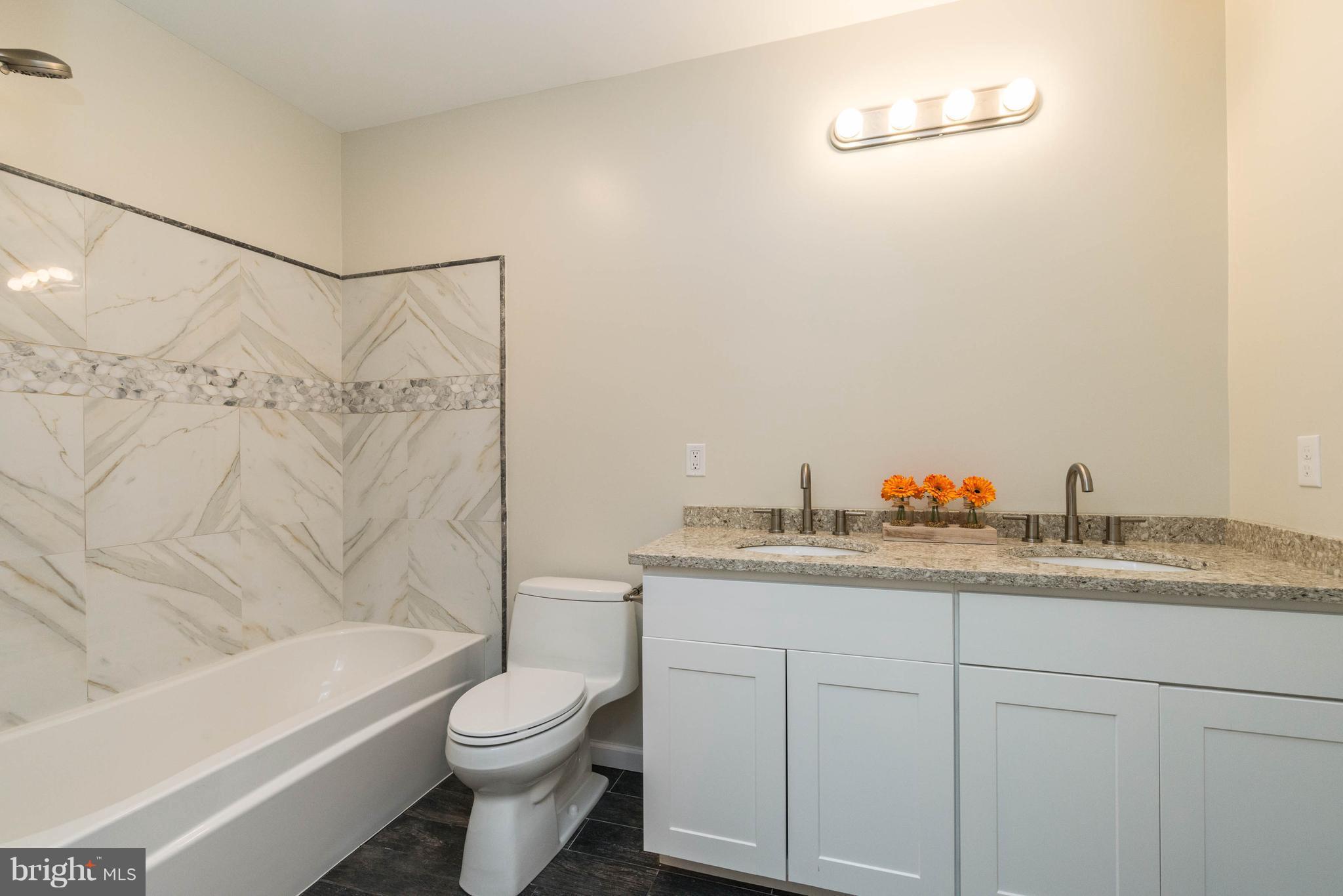 8220 Mission Road Jessup, MD 20794 - Photo 15 of 28 a bathroom with a granite countertop toilet a sink and bathtub