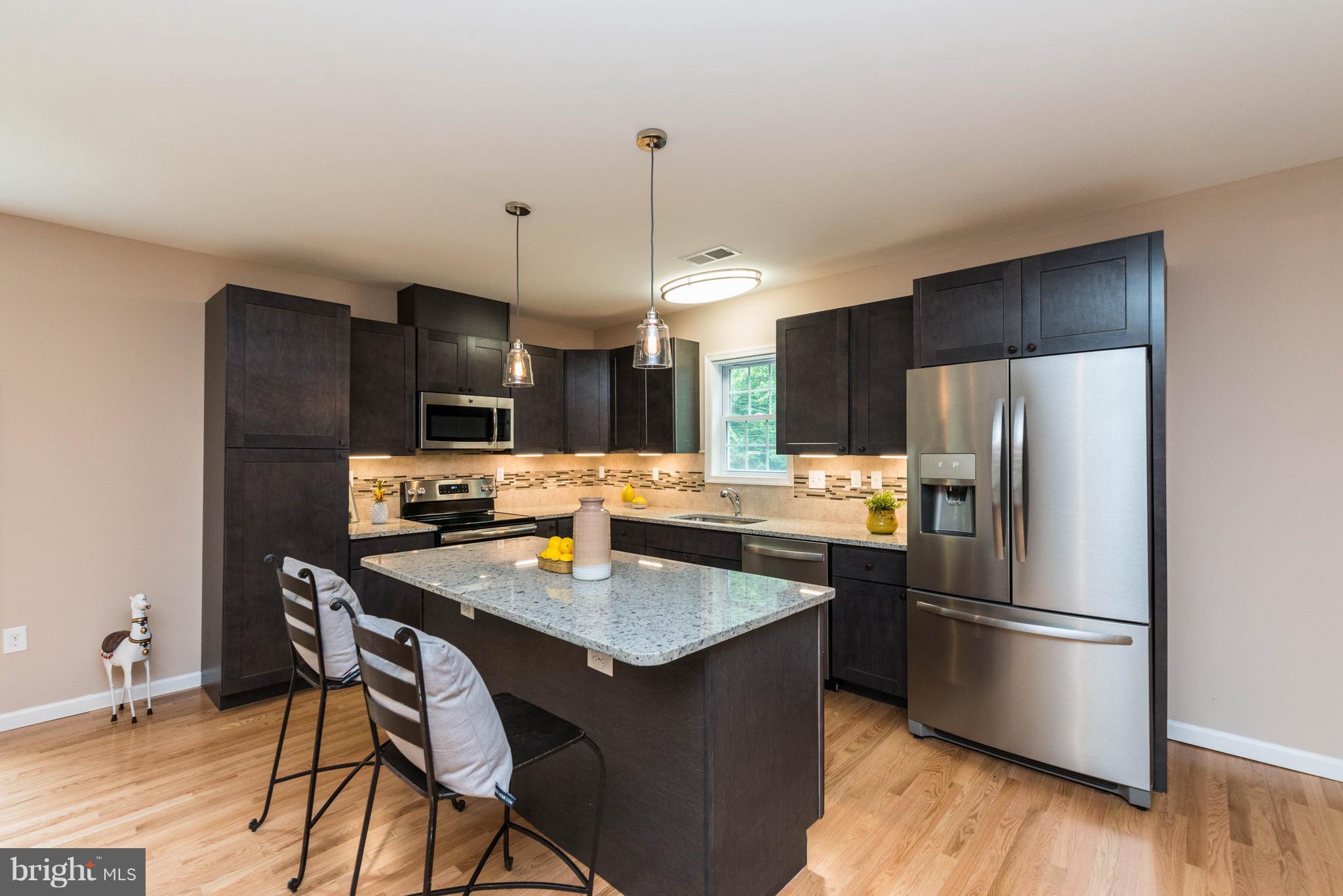 8220 Mission Road Jessup, MD 20794 - Photo 25 of 28 a kitchen with stainless steel appliances a dining table chairs refrigerator and stove
