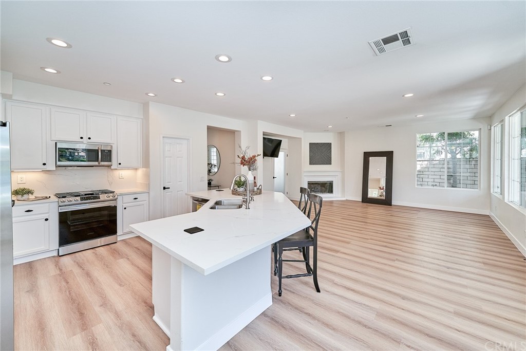50 Lakeside Drive Buena Park, CA 90621 - Photo 32 of 69 a large white kitchen with a stove a sink dishwasher and a refrigerator with wooden floor