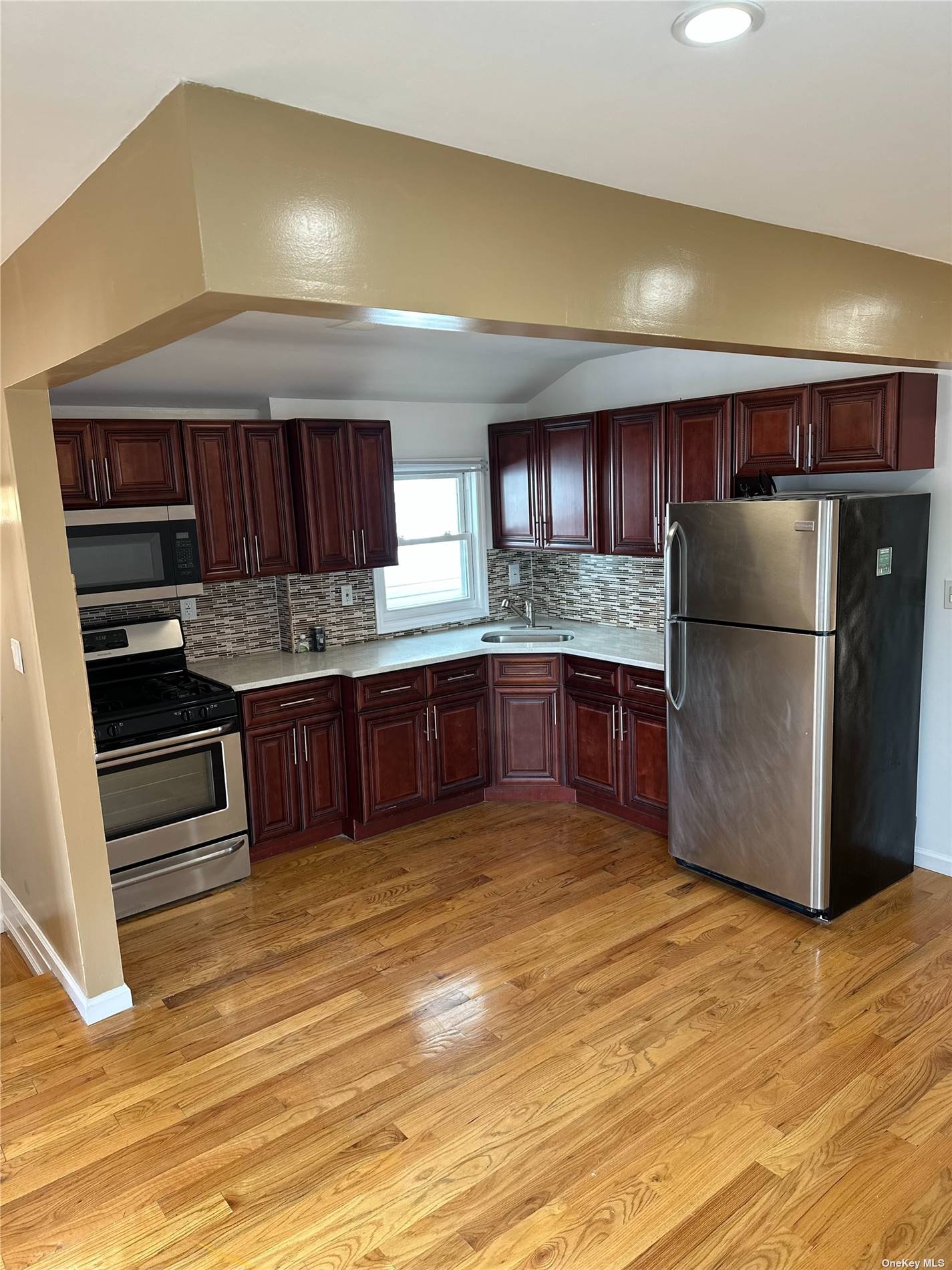 a kitchen with stainless steel appliances kitchen island granite countertop a refrigerator cabinets and wooden floor