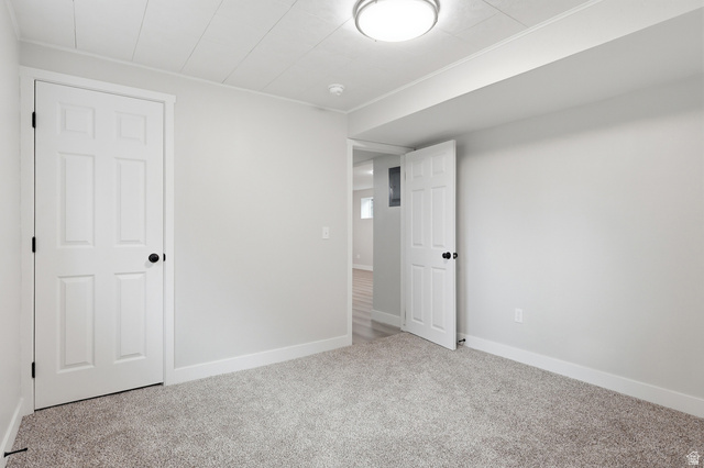 629 King Circle Layton, UT 84041 - Photo 21 of 26 Light gray carpeting in a neutral-toned room featuring a white six-panel door with black hardware, white baseboards, and a white plank ceiling with a flush-mount light fixture