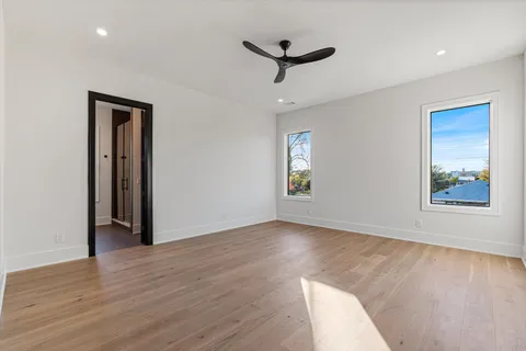 an empty room with wooden floor and ceiling fan