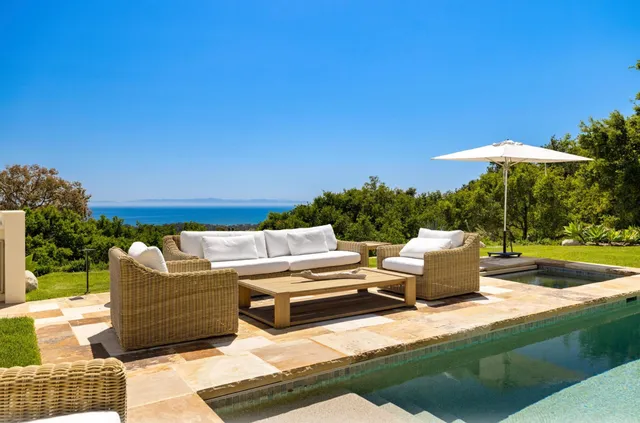 a view of a patio with couches and table and chairs under an umbrella