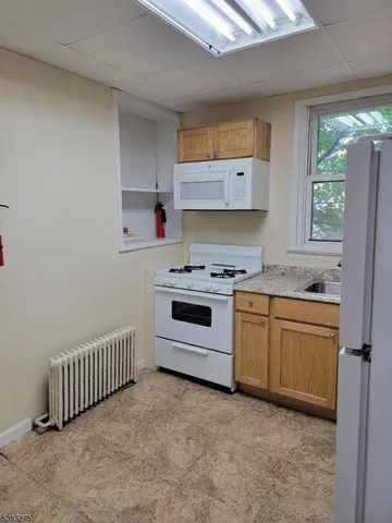 a kitchen with granite countertop a stove a sink and a refrigerator