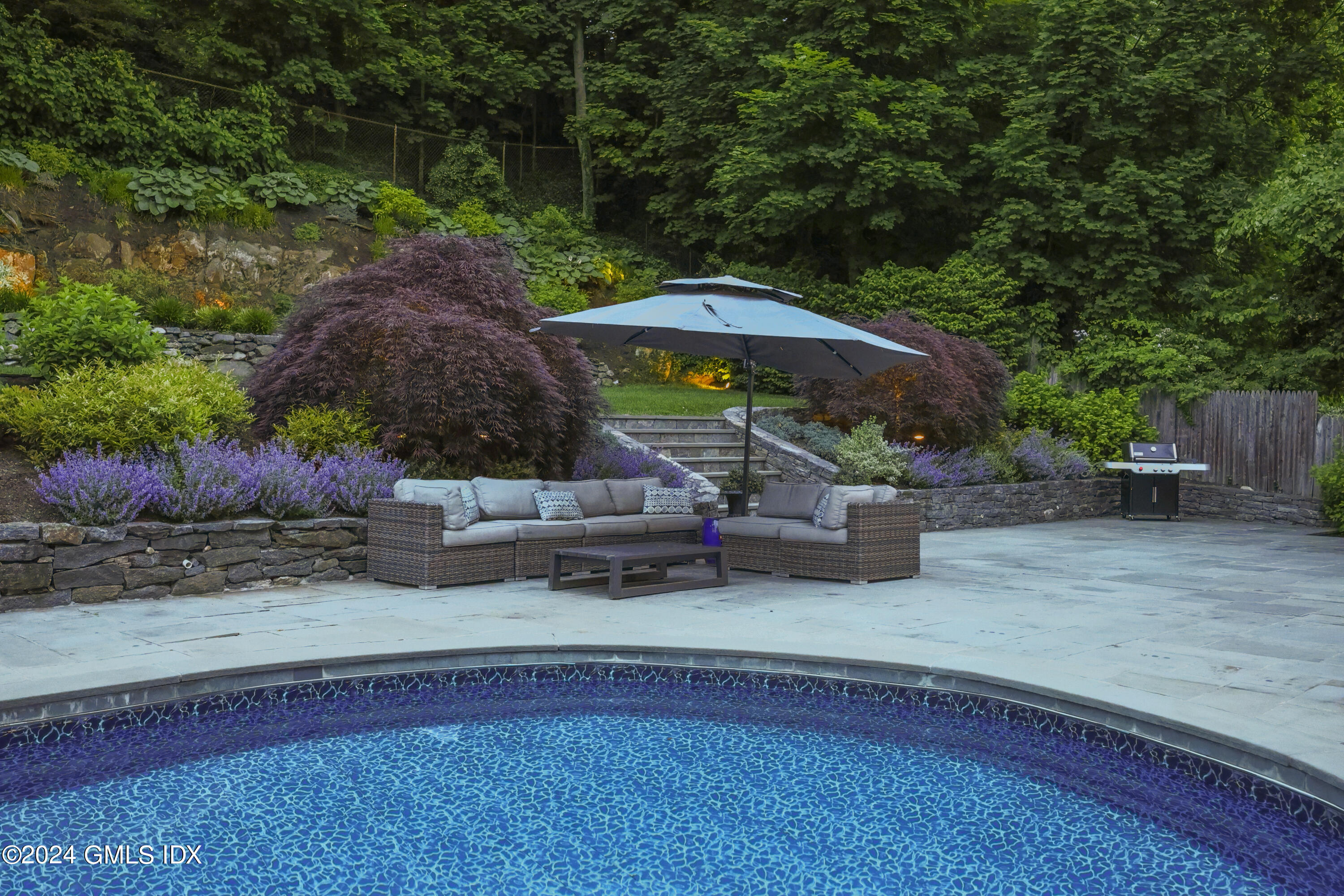 85 Mallard Drive Greenwich, CT 06830 - Photo 36 of 45 a backyard of a house with table and chairs under an umbrella
