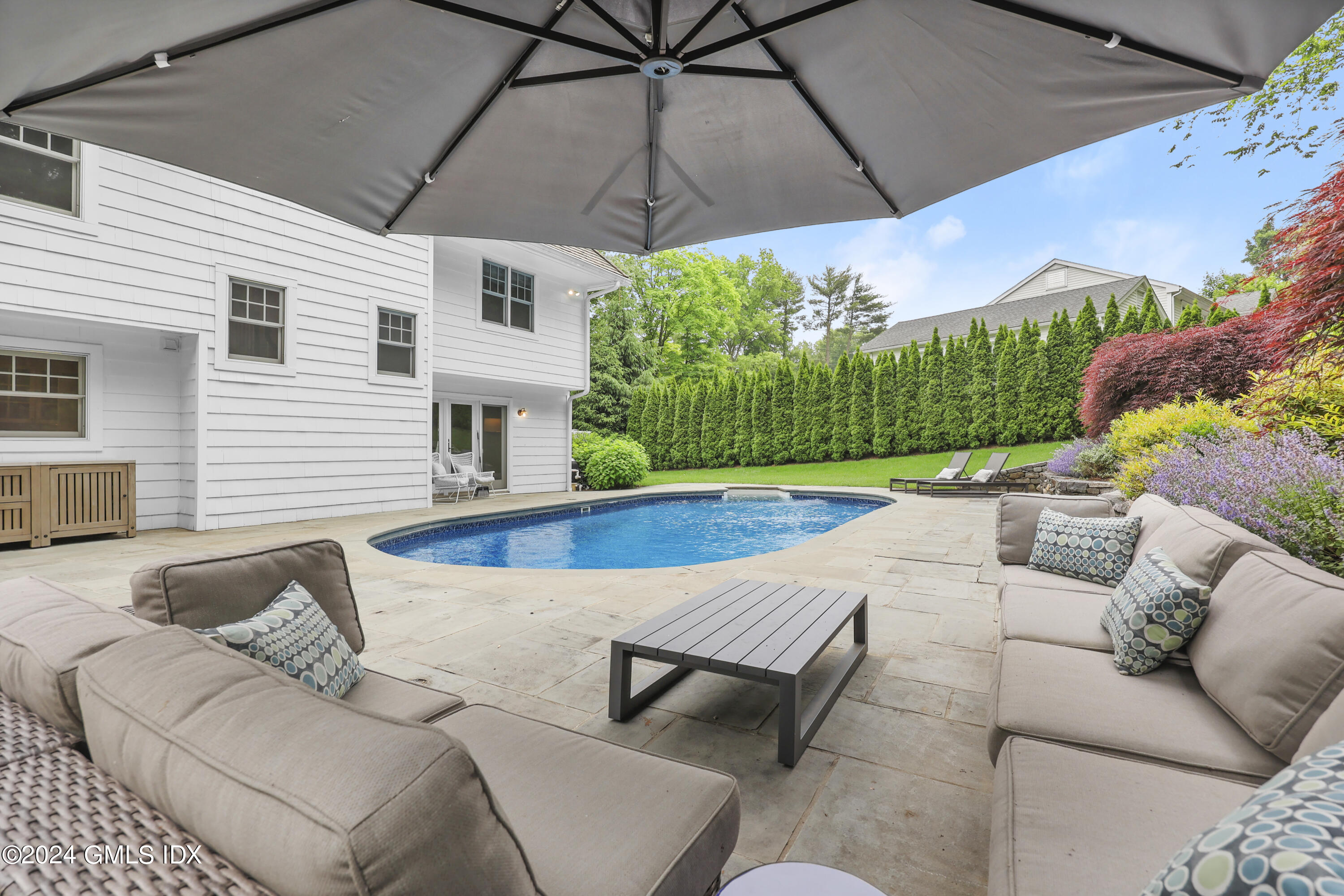 85 Mallard Drive Greenwich, CT 06830 - Photo 7 of 45 a view of a patio with couches table and chairs under an umbrella