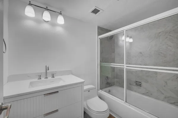 a bathroom with a shower sink vanity mirror and toilet