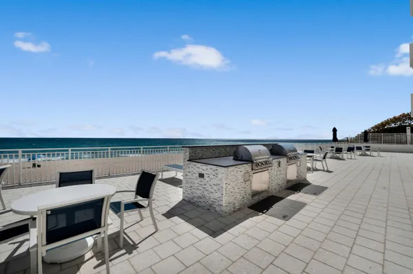 a roof deck with table and chairs a barbeque with potted plants