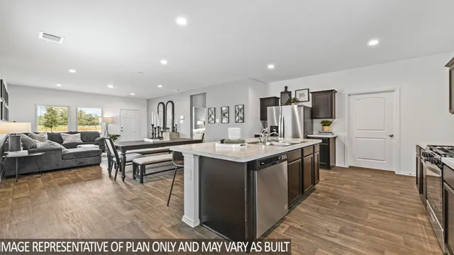 a large kitchen with stainless steel appliances a large counter top a couch and a view of living room