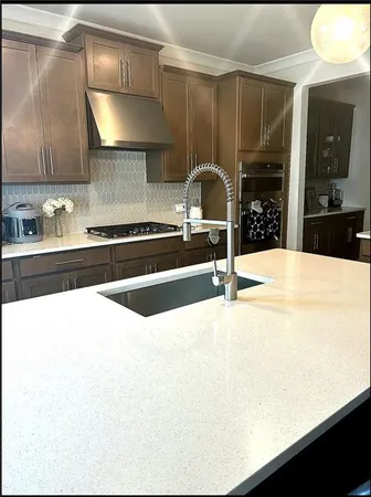 a kitchen with stainless steel appliances kitchen island granite countertop a sink a stove and cabinets