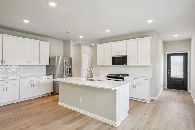 a kitchen with stainless steel appliances a stove top oven a sink a refrigerator and cabinets