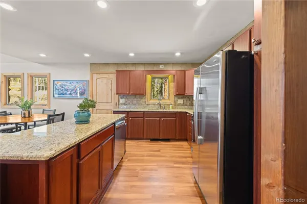 a large kitchen with granite countertop a large counter top stainless steel appliances and cabinets
