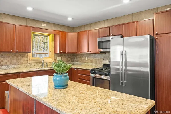 a kitchen with stainless steel appliances granite countertop a refrigerator a sink a stove a oven with wooden cabinets