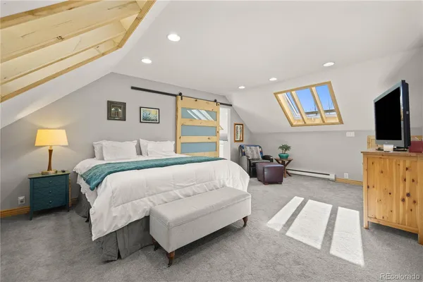 a spacious bedroom with a bed and a flat screen tv