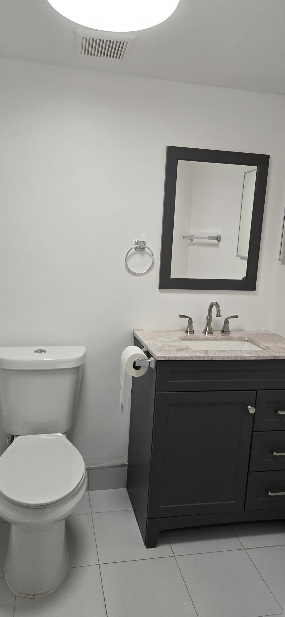 497 Flanders K Delray Beach, FL 33484 - Photo 12 of 15 a bathroom with a toilet sink and mirror