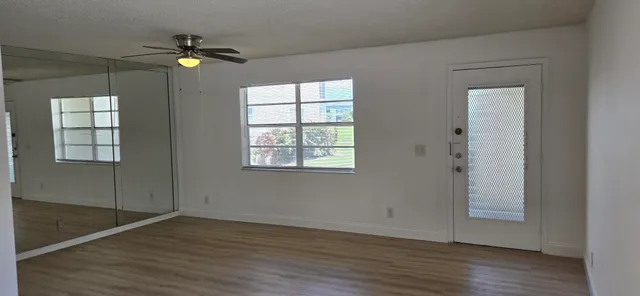 an empty room with wooden floor closet and windows