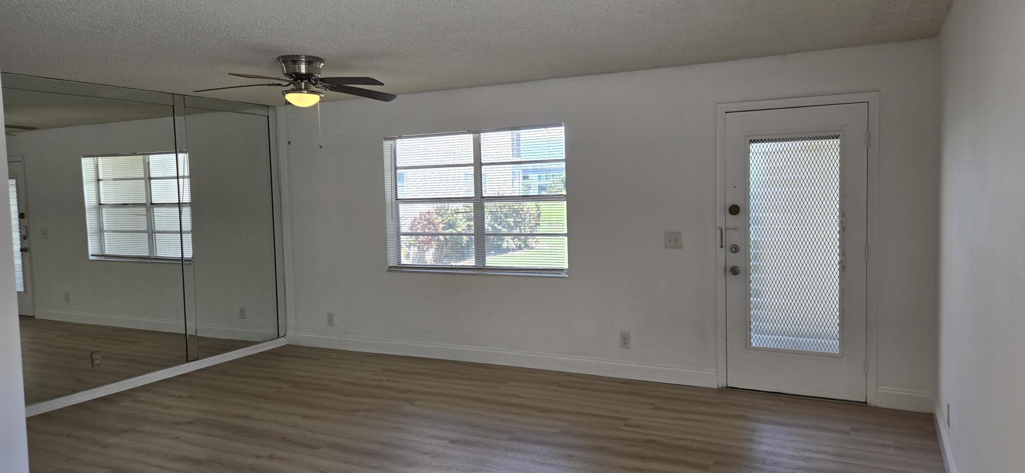 497 Flanders K Delray Beach, FL 33484 - Photo 5 of 15 an empty room with wooden floor closet and windows