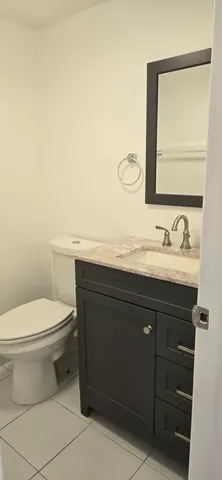 a bathroom with a granite countertop toilet sink and mirror