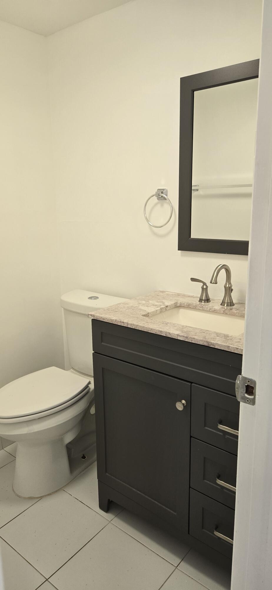 497 Flanders K Delray Beach, FL 33484 - Photo 8 of 15 a bathroom with a granite countertop toilet sink and mirror
