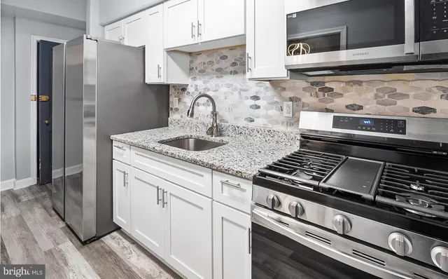 a kitchen with granite countertop a sink stove and cabinets