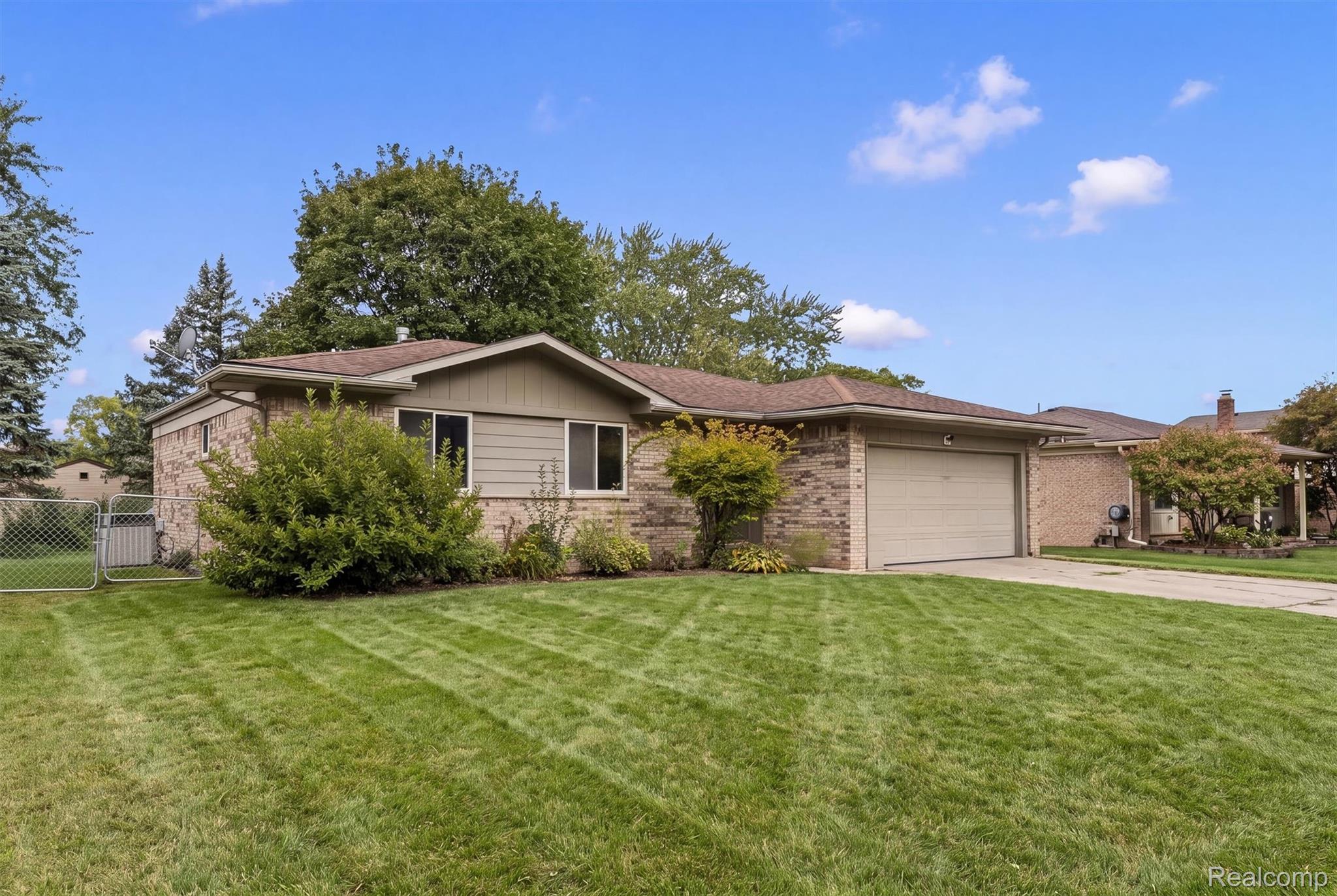 39861 Rager Court Clinton Township, MI 48038 - Photo 3 of 26 Brick and siding exterior with an attached garage, paved driveway, and mature landscaping