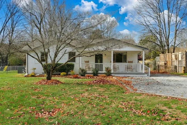a front view of a house with a garden and trees