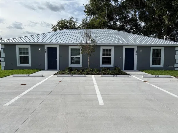 a front view of a house with yard and parking