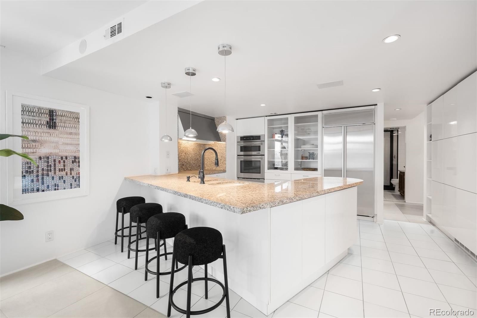 1777 Larimer Street, Unit 710 Denver, CO 80202 - Photo 12 of 47 a large kitchen with kitchen island a chandelier and living room view