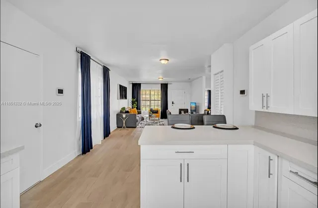 a view of a kitchen with kitchen island a sink wooden floor and living room view