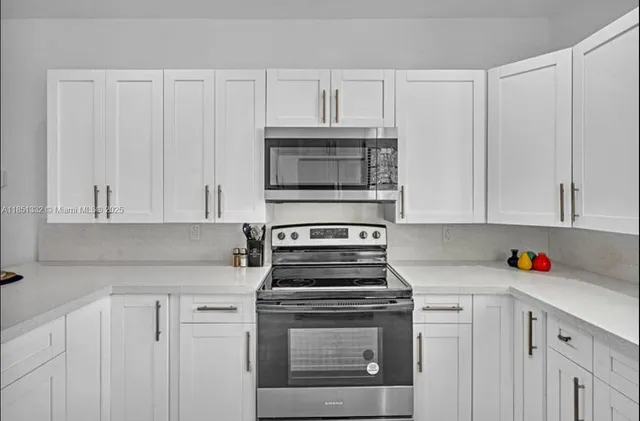a kitchen with granite countertop white cabinets and stainless steel appliances